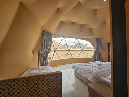 two beds in a room with a large window at Salma Desert Camp in Wadi Rum