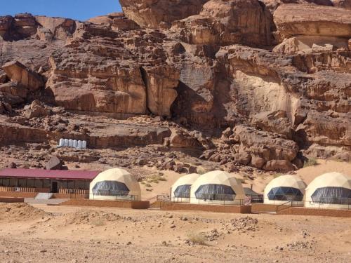 a group of domes in the desert next to a cliff at Salma Desert Camp in Wadi Rum