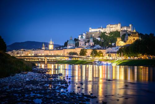 a view of a city at night with a river at Apartments Salzburg - Bergstraße in Salzburg