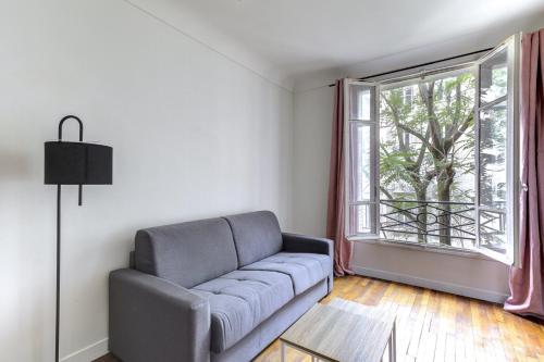 un salon avec un canapé et une fenêtre dans l'établissement 569 Suite Monceau - Superbe Appartement à Paris, à Paris