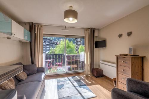 un salon avec un canapé et une grande fenêtre dans l'établissement Studio du Brévent - Welkeys, à Chamonix-Mont-Blanc