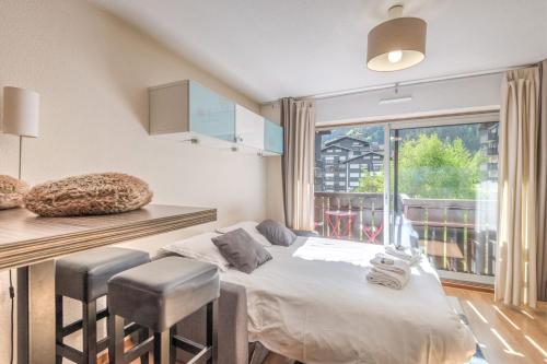 - une chambre avec un lit, deux tabourets et une fenêtre dans l'établissement Studio du Brévent - Welkeys, à Chamonix-Mont-Blanc