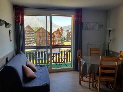 d'un salon avec un canapé et une table ainsi que d'un balcon. dans l'établissement Joli studio 4-6 pers - balcon avec vue sur montagne, à Saint-Étienne-en-Dévoluy