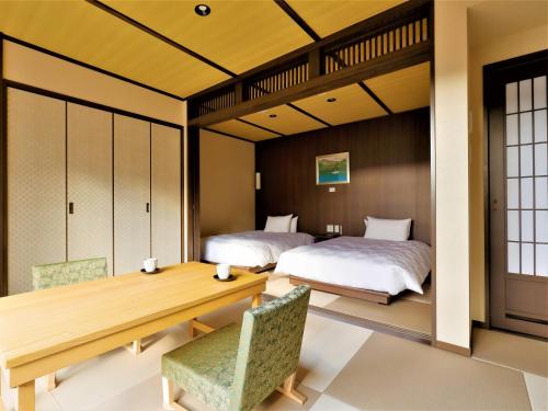 a bedroom with two beds and a table and chairs at Hotel Morinokaze Hakone Sengokuhara in Hakone