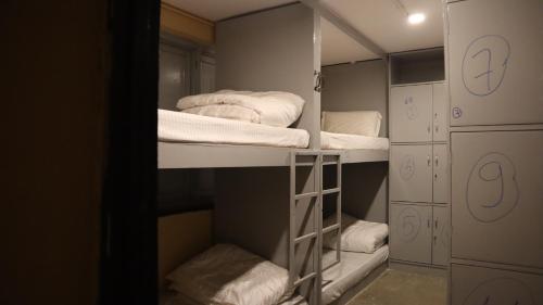 a walk in closet with three bunk beds and towels at Heranya Hostel in Kathmandu