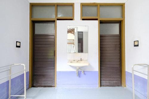 a bathroom with a sink and two doors and a mirror at Wisma 812 Khusus Putra for Male Only in Bandung