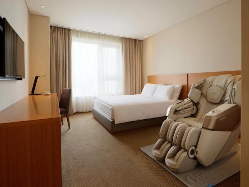 a hotel room with a bed and a couch and a television at LOTTE City Hotel Ulsan in Ulsan