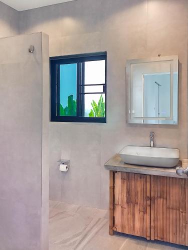 a bathroom with a sink and a mirror and a window at Villa et Bungalow Baan Joan Khao Lak in Khao Lak