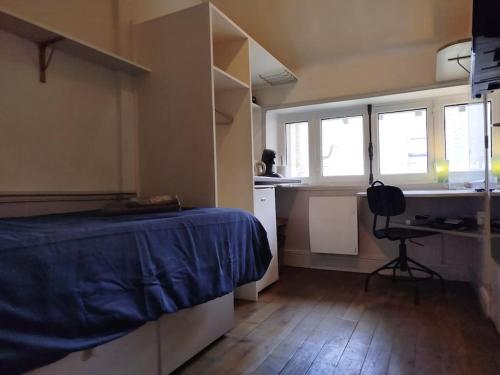une chambre avec un lit et un bureau et deux fenêtres dans l'établissement Studette Cathédrale, à Reims