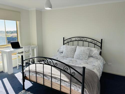 Un dormitorio con una cama y un escritorio con una computadora portátil. en Nellies Hideaway 1-20 Troon Drive, en Normanville