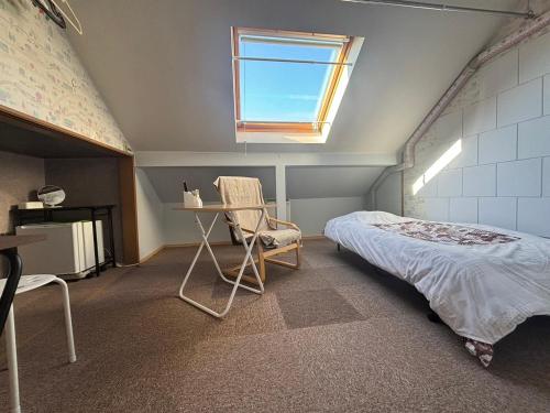 a bedroom with a bed and a chair and a window at Guest House モモ in Obihiro