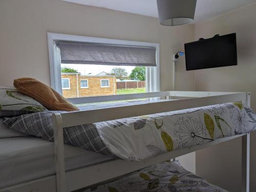 a bed in a room with a window and a couch at Hemsby Holiday Home - Norfolk beach & seaside fun in Great Yarmouth