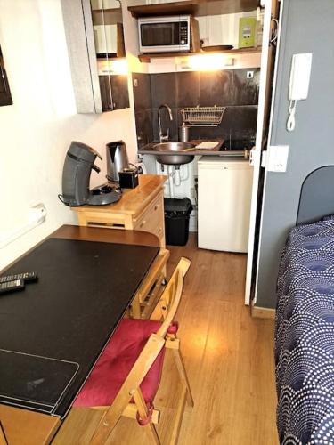 - une petite cuisine avec un bureau et un lit dans une chambre dans l'établissement Studette Place Jamot, à Reims