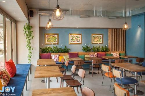 a restaurant with tables and chairs in a room at Joy Cafe&Bakery Apartments in Skopje