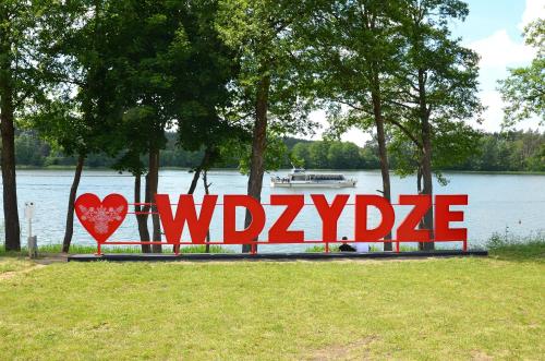 un panneau indiquant wyssride en face d'un lac dans l'établissement Weranda, à Wdzydze Kiszewskie