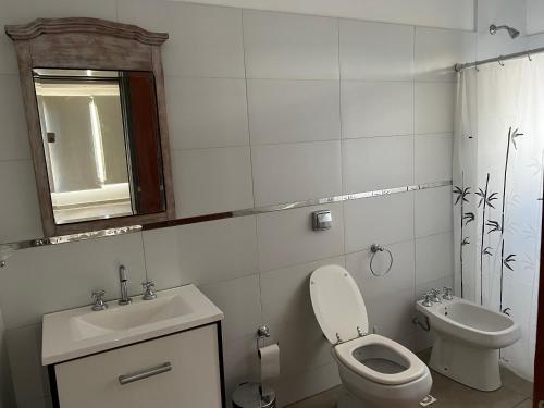 een witte badkamer met een toilet en een wastafel bij Balcón al río in Villa Carlos Paz