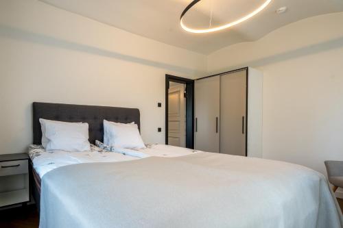 a bedroom with a large white bed and a chandelier at Elias Apartments in Pärnu