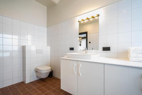 a white bathroom with a sink and a toilet at Elias Apartments in Pärnu