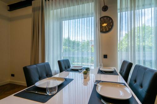 a dining room table with chairs and a clock on a window at Elias Apartments in Pärnu