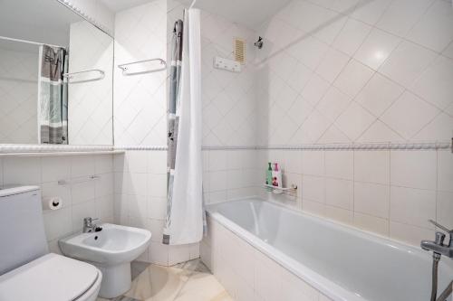 een badkamer met een bad, een toilet en een wastafel bij Kiko Las Americas in Isla Cristina