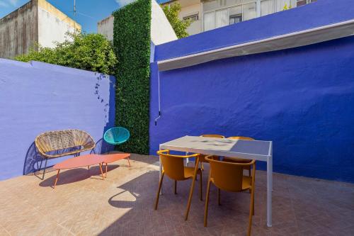 un tavolo e sedie di fronte a una parete blu di Fonz Patio House a Setúbal