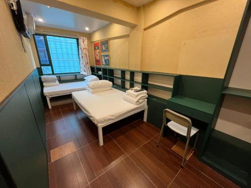 Habitación pequeña con 2 camas y silla en Venetian Hostel, en Hong Kong