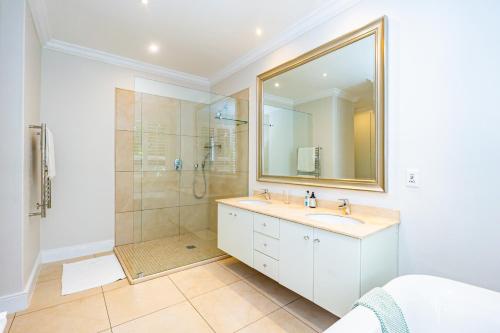 a bathroom with a shower and a sink and a mirror at Boundary Lane, Dunkirk Estate in uMhlali