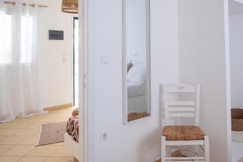 Camera bianca con specchio e sedia di Spiti Apartment a Mylopotas