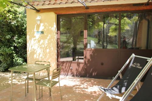 a patio with a table and chairs and a glass door at Clos Saint-Michel Resort & Spa in Malaucène