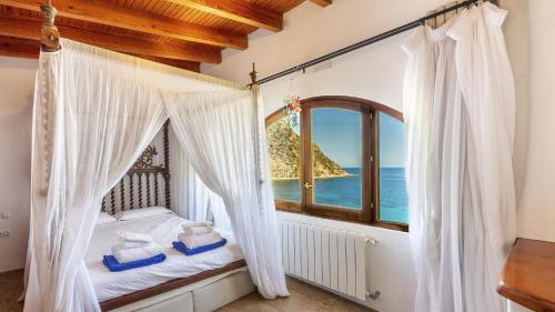 ein Schlafzimmer mit einem Bett und einem Fenster mit Blick auf das Meer in der Unterkunft Villa Lunablanca in Santa Eulària des Riu