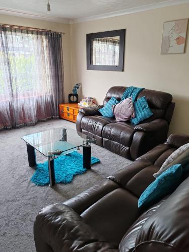 a living room with a leather couch and a glass table at Wallace View - Holiday Home in Stirling