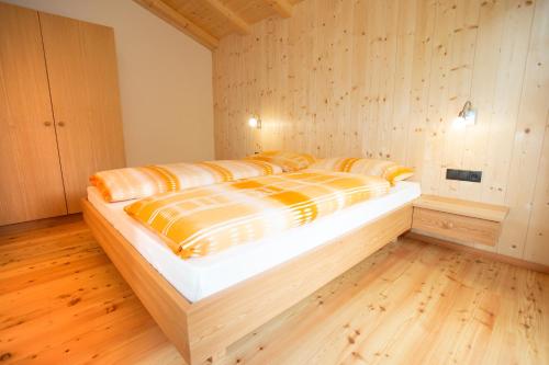 a large bed in a room with wooden floors at Anderleithof in Senales