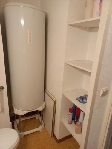 a white bathroom with a toilet and shelves at Appartement Le Verdon sur mer in Le Verdon-sur-Mer