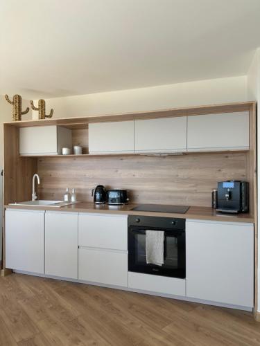 une cuisine avec des armoires blanches et un four noir dans l'établissement La Tour Alba, à Valras-Plage