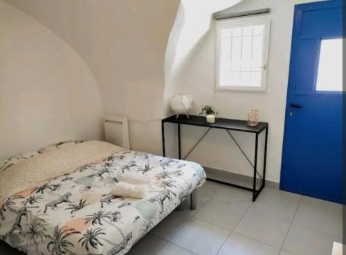 - une chambre avec une porte bleue, un lit et une table dans l'établissement La Petite Voute Montpellier Reine, à Montpellier