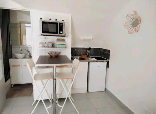 une petite cuisine avec une table et des chaises. dans l'établissement La Petite Voute Montpellier Reine, à Montpellier