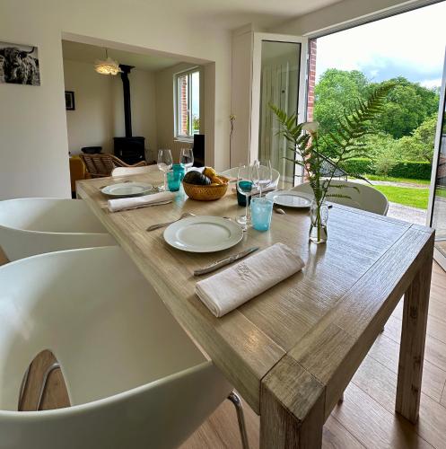 une table en bois avec des assiettes et des verres dans l'établissement Carnets de Voyages Maison 4 à 6 personnes, à Hautot-sur-Mer