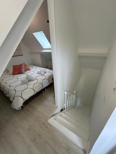 a attic bedroom with a bed and a staircase at Carnets de Voyages Maison 4 à 6 personnes in Hautot-sur-Mer
