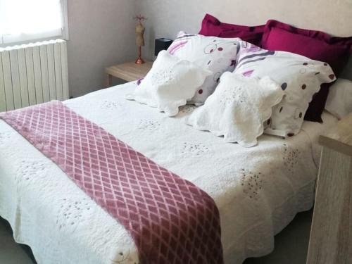 - un lit avec des draps et des oreillers violets et blancs dans l'établissement Gîte Pavillon Kifadonfe 3 ch avec cour et jardin clos, à Saint-Germain-Lembron