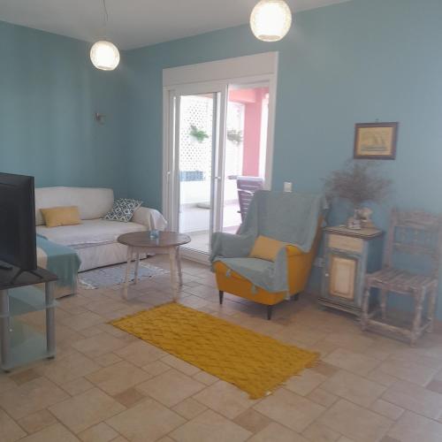a living room with a couch and chairs and a tv at Acharavi, villa next to the beach in Acharavi