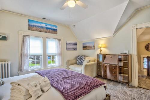 a bedroom with a bed and a chair and windows at Victorian Charm With Hot Tub & Fire Pit Downtown in Colorado Springs