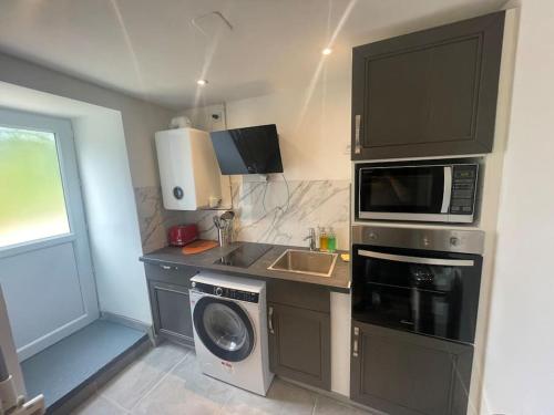 a kitchen with a washing machine and a microwave at Le Duplex Balnéo Maison climatisée in Saint-Martin-du-Tertre