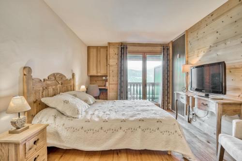 une chambre avec un grand lit et une télévision dans l'établissement Marmots, à Megève