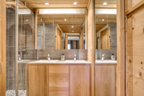 une salle de bain avec trois lavabos et deux miroirs dans l'établissement Marmots, à Megève