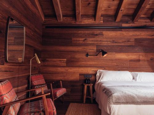 um quarto com paredes de madeira e uma cama e cadeiras em L´Ovella Negra Mountain Lodge em Canillo