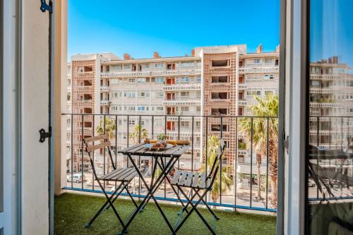 une table et des chaises sur un balcon avec vue sur un immeuble dans l'établissement Le Mayol - T3 Clim & Balcon, à Toulon