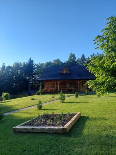 a log cabin with a garden in front of a house at Domek u Heli in Limanowa