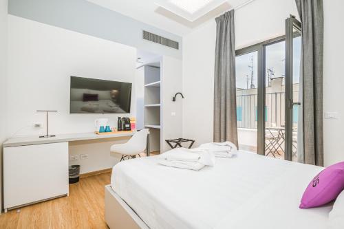 a white bedroom with a bed and a desk and window at Dotcampus Roma City Center in Rome