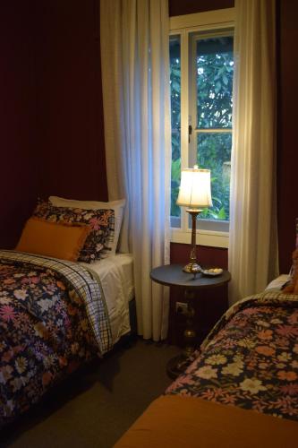 a bedroom with two beds and a window with a lamp at The Rustic Nest Yarramalong in Yarramalong