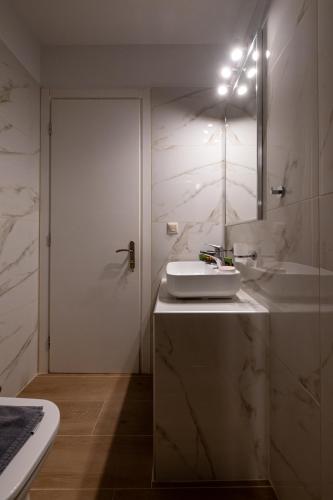 a white bathroom with a sink and a tub at Abeloessa Methonian Hospitality in Methoni